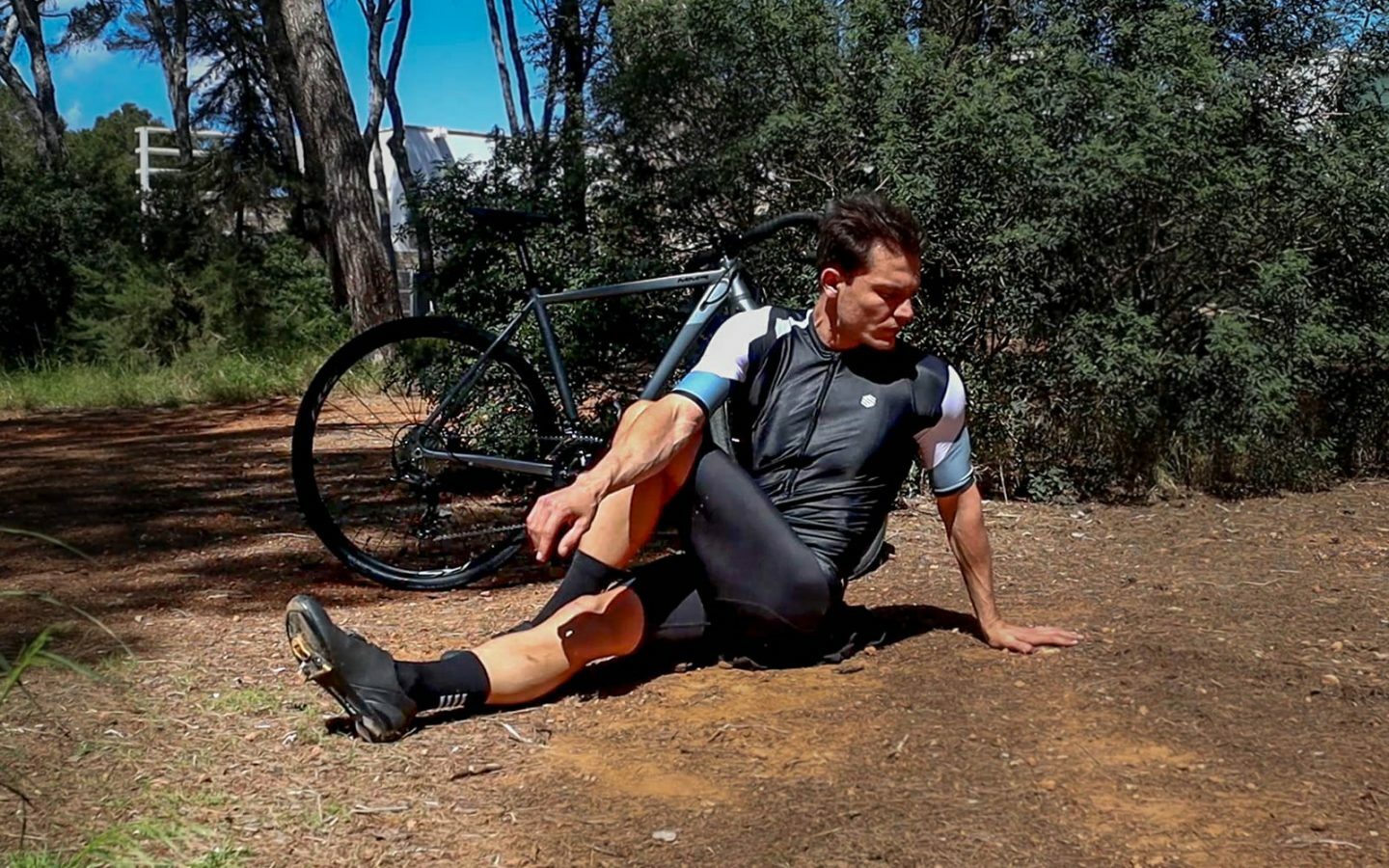 Estiramiento de piernas, fitness y hombre en bicicleta en una carretera con  una bicicleta en las montañas para cardio, viajes y ejercicios deportivos  en la naturaleza. Atleta haciendo un cálido Fotografía de